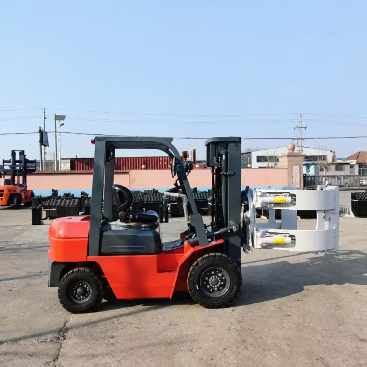 Unbranded red diesel forklift truck with attachment in an industrial yard